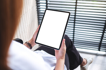 Mockup image of a woman holding digital tablet with blank white desktop screen in office