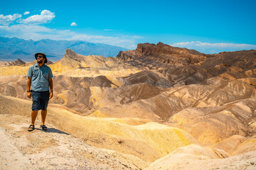 Fototapeta na wymiar A man with a green shirt on the beautiful viewpoint of Zabriskre Point, California. United States