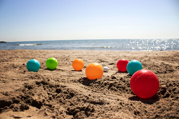 playing pétanque on the beach, I play colored balls on sand under blue sky and sea
