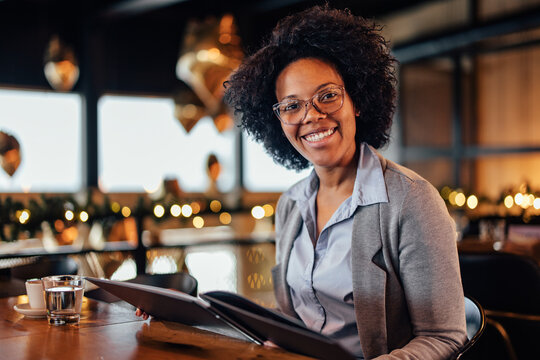 Portrait of cheerful African-American woman, sitting in the hotel restaurant.