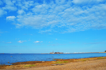 The northern coast of the Gulf of Finland. Sandy beach, blue calm sparkling sea and blue sky. Russia.