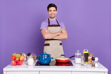 Photo of pretty confident guy wear grey apron arms crossed ready cook tasty dish isolated violet...