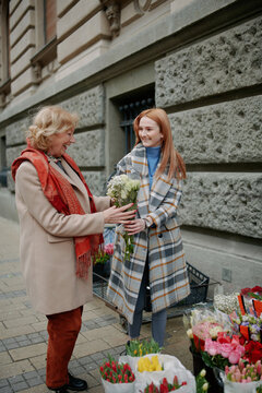 Granddaughter buying flowers for her grandmother on a street.