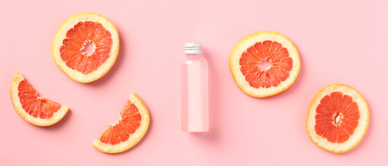 Vitamin c citrus lotion bottle with slices of grapefruit on pink background. SPA body treatment...