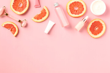 Vitamin c citrus beauty products with slices of grapefruit on pink background. Face and body skin care concept. Flat lay, top view.