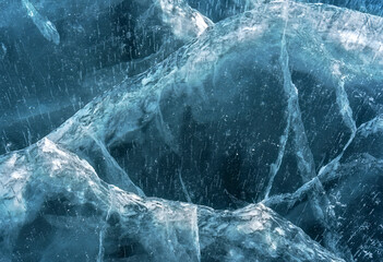 Transparent blue ice of frozen Baikal lake with waves pattern. Beautiful winter nature background.