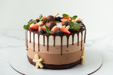 Brown layered cake Three chocolates decorated with bluberries, strawberries and chocolate drips on...