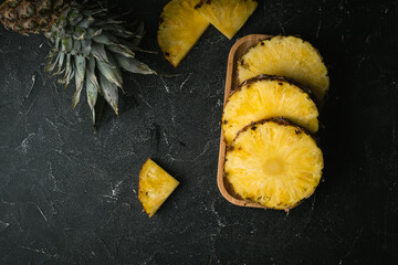 ripe pineapple cut into slices on a black background. top view