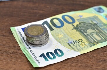 100 euro banknotes and metallic coins on brown table