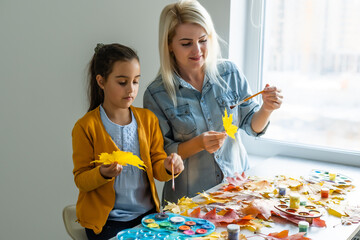 mother and daughter paint autumn leaves