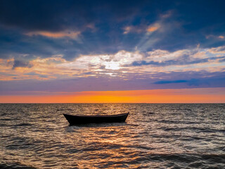 Silhouette of an empty boat in the sea at sunset background. Beautiful sunset with a fishing boat.