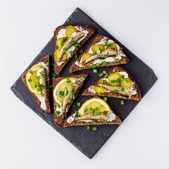 canapes with sprats on a black stone tray