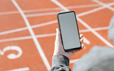 Sportswoman using mobile phone mockup in stadium outdoors. Close-up of woman's hand holding...
