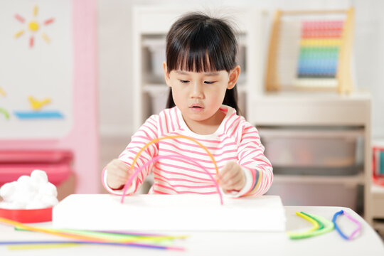 Young Girl Making Rainbow Craft Using Pipe Cleaner At Home