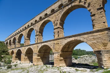 Poster de jardin Pont du Gard Famous Pont du Gard - an iconic Ancient Roman bridge, aqueduct and engineering masterpiece in the region Provence, France. It is formed by three floors of arcades, massive arches and pillars