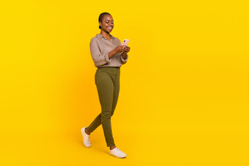 Fototapeta na wymiar Photo of cheerful positive lady dressed checkered shirt earphones walking empty space isolated yellow color background