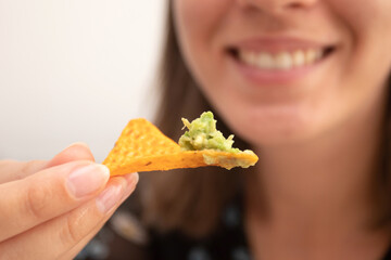 Beautiful woman eating nachos chips with guacamole dip