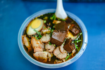 Street food noodles put in plastic cups and plastic spoons.