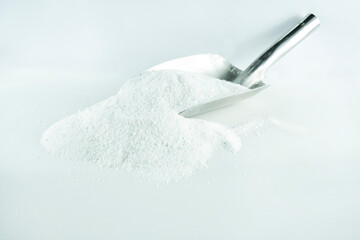 Pile of detergent washing powder with metal scoop shovel, isolated on white background, sitting view, close-up, detergent washing powder for washing machine