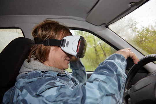 Virtual glasses in the car. Test drive of a new car with virtual reality. A picture of a young man sitting behind the wheel wearing virtual reality headphones.