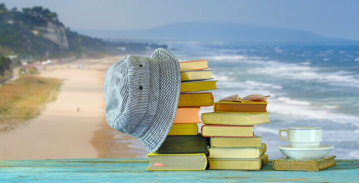 Stack Of Books, Sun Hat And Sunglasses In Front Of Beautiful Seascape, Reading In The Summer Holidays And Relaxing Concept