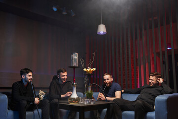 a company of young men smokes a hookah in an atmospheric cafe with a hookah