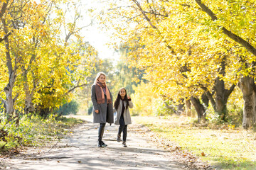 Fototapeta premium Young mother playing with her daughter in autumn park
