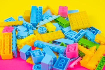 Colorful blocks toy, colored background, playing and learning concept, spilled kid toys, building blocks, yellow and pink backdrop, top view