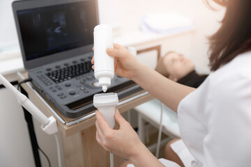 Closeup hands of woman doctor preparing for ultrasound device scan. Gynecologist applies gel on...