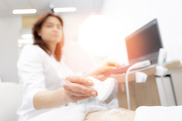Obraz na płótnie Canvas Ultrasound scanner device in hand of professional doctor woman examining patient female, sunlight