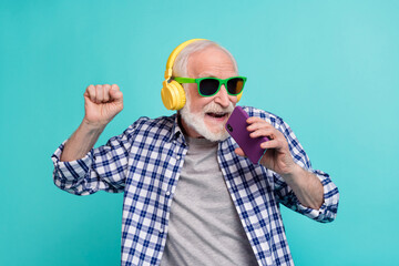 Portrait of excited crazy grandpa hold telephone singing enjoy new single isolated on teal color...