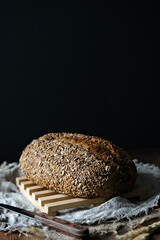 Craft bread on a linen tablecloth. Sourdough bread. Sour bread. Whole grain bread. Dark mood.