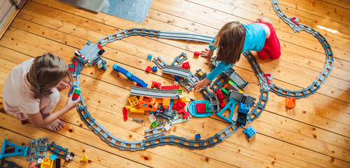 Girls, sisters play kids constructor, build toy railway, railroad by Bricks bricks,blocks. Train,...