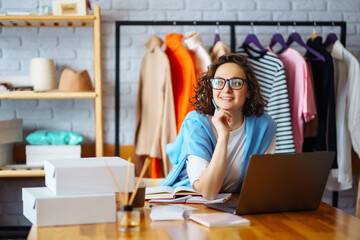 Smiling woman takes notes of orders from with laptop. Dropshipping owner works, checks the order...