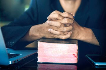 Business man praying and put hands on the bible, Christian concept.