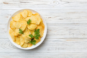 Potato chips on bowl with napkin on colored background. Delicious crispy potato chips in bowl. Space for text. Top view