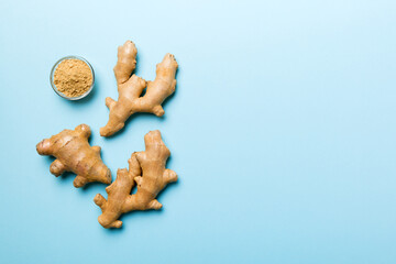 Finely dry Ginger powder in bowl with green leaves isolated on colored background. top view flat lay