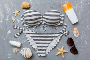 Woman swimwear and beach accessories flat lay top view on colored background Summer travel concept. bikini swimsuit, straw hat and seasheels. Copy space Top view