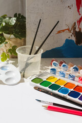 Leisure time. Painting a picture of a house with paints on canvas. Paints, brushes and canvas close-up on the table. Home hobby, recreation.