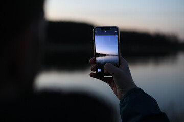 hand holding smart phone and taking photo of beautiful sunset