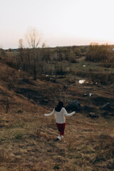 The amazing female is posing with her hands and looking at the sunset. There is a big cornfield near the girl.