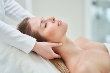 Fototapeta na wymiar Young nice woman having face massage in spa