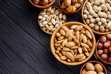 set of different nuts on a black rustic wooden background
