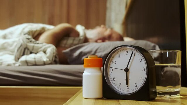 Slow motion. Morning intake of vitamins or medications by time.  Time for the concept of drugs. An elderly sick person chooses with the help of medical tablets for hands from the table
