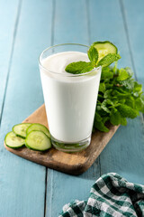 Ayran drink with mint and cucumber in glass on blue wooden table