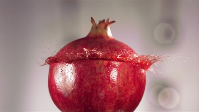 Half Pomegranate falling and splashing on white background. Food levitation concept. Slow Motion