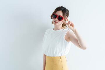 ハートのサングラスをかけてピースサインをする女性