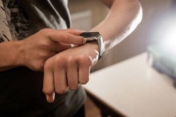 A man adjusts his smartwatch. Nice blurry background.