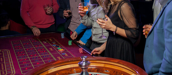 People play poker roulette at the table. Friends playing in the casino. A group of young people at...