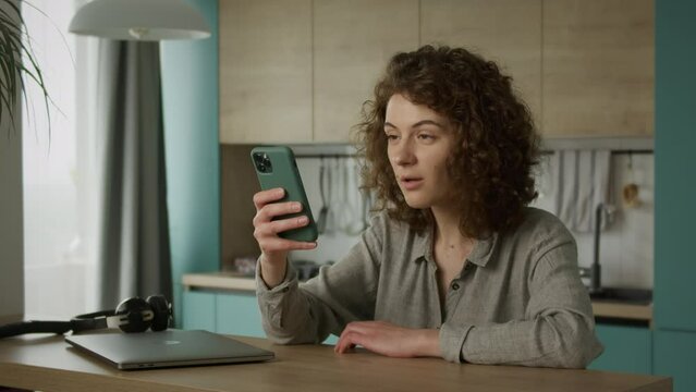Young 20s adult student reading something weird on her smartphone indoors